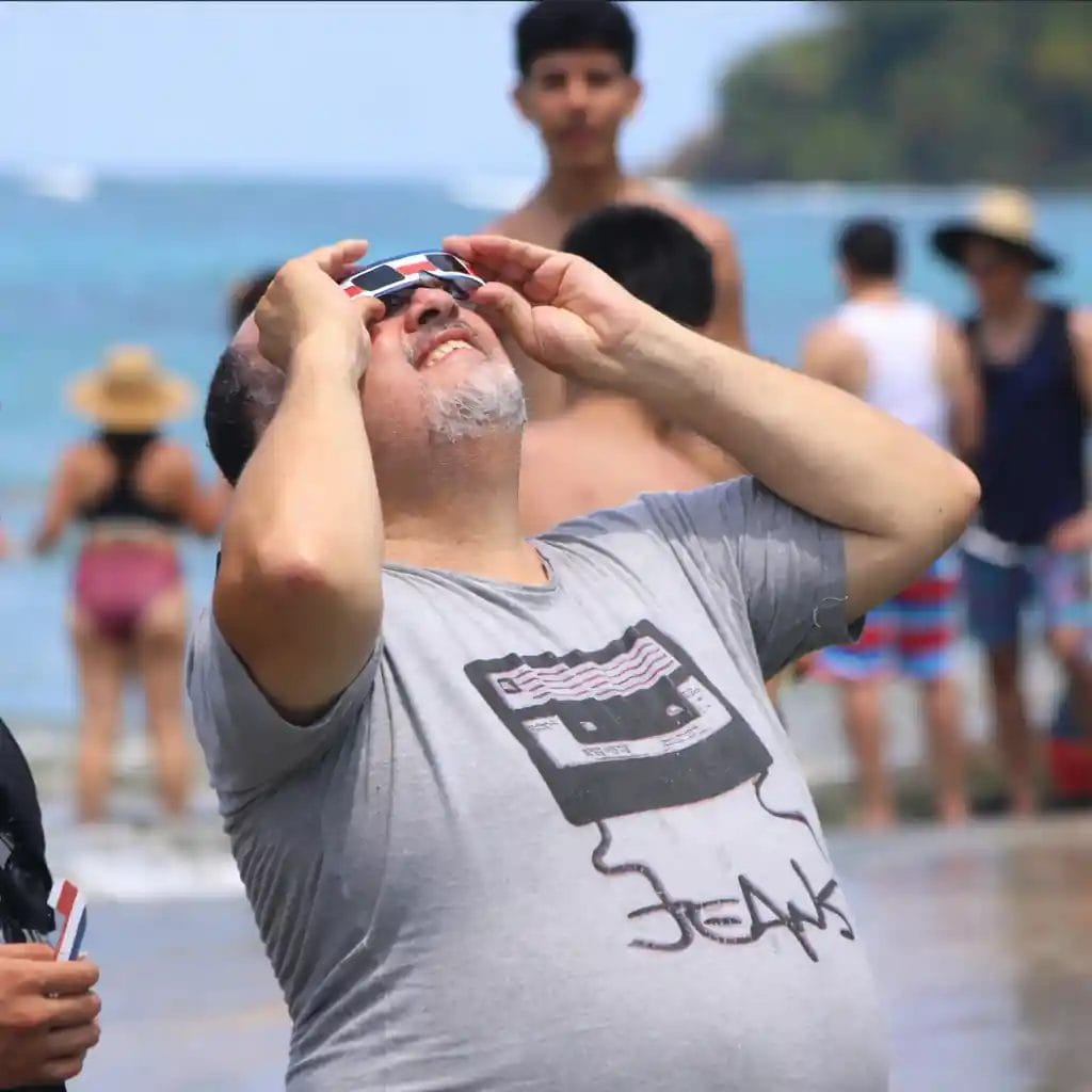 Person using costa rica themed solar eclipse glasses at the beach.
